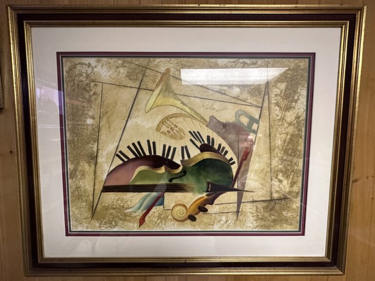A Fine Quality LE Print by Listed Artist Emanuel Mattini (Persian, b. 1966), 36 3/4 inches x 27 1/2 inches, framed. The artwork is a complex and abstract print featuring a juxtaposition of musical instruments, mainly a trumpet, a piano keyboard, and what appears to be a stringed instrument like a violin or viola. Earthy tones and pastel colors create a dreamlike atmosphere, while the textured background suggests a sense of age or antiquity. The placement of the musical elements seems to defy gravity, evoking a feeling of surrealism or expression of music’s timeless and ethereal nature.