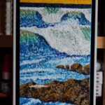 “Big Day,” a 10″x29″ acrylic on canvas, exemplifies Ron Sanford’s pointillism, capturing a formidable wave’s cresting power against rugged rocks, set under a dramatic, fiery sky. This framed piece juxtaposes the ocean’s vibrant blues with the warm, explosive colors of a high-energy day.