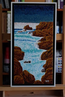 “White Water Alley,” a 10″x20″ acrylic on canvas, brings to life a coastal inlet using Sanford’s signature pointillist approach. Vivid dots define the turbulent white waters that weave through rugged, rocky outcrops, contrasting with the serene blues of the sea, all under a textured sky, framed and signed.